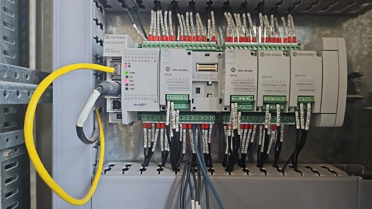 Tablero de control abierto con controlador, módulos de comunicación y borneras cableadas