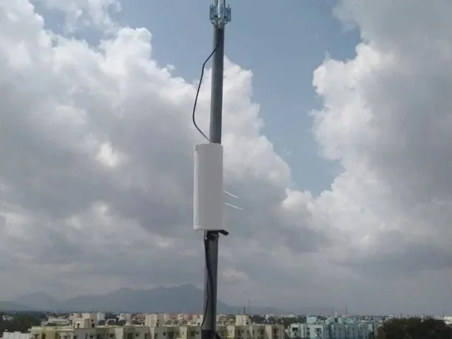 Antena exterior montada en un mástil con edificios de fondo