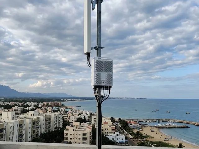 Ilustración de una antena exterior con su gabinete de comunicaciones sobre una terraza frente a una localidad costera